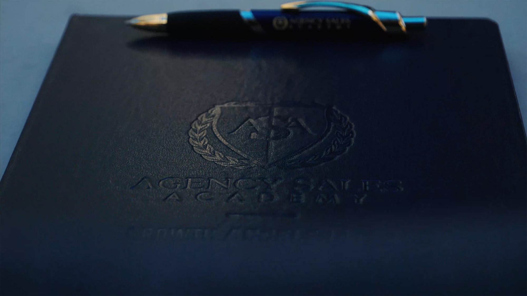 Closeup of Agency Sales Academy portfolio and pen